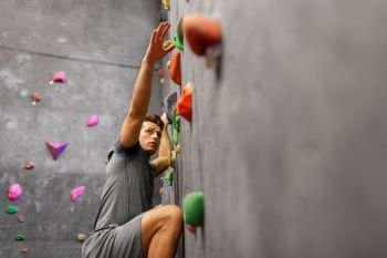 fitness, extreme sport, bouldering, people and healthy lifestyle concept - young man exercising at indoor climbing gym. young man exercising at indoor climbing gym