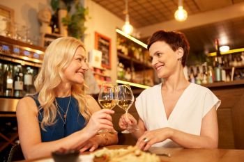people, celebration and lifestyle concept - happy women drinking wine and clinking glasses at bar or restaurant. happy women drinking wine at bar or restaurant