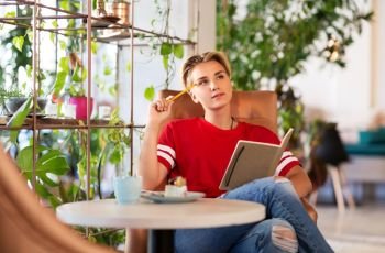 people, leisure and inspiration concept - woman or teenage girl with notebook at coffee shop or cafe. teenage girl with notebook at coffee shop or cafe