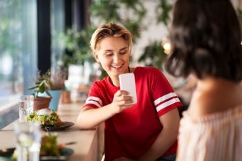 leisure, technology and people concept - female friends having lunch and photographing by smartphone at restaurant or cafe. women having lunch and photographing at cafe