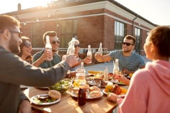 leisure and people concept - happy friends toasting drinks dinner or barbecue party on rooftop in summer. happy friends toasting drinks at rooftop party