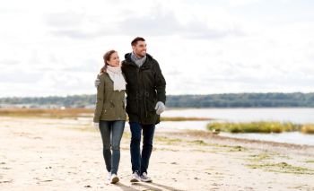 love, relationship and people concept - smiling couple walking along autumn beach and hugging. couple walking along autumn beach