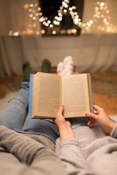 leisure, hygge and christmas concept - close up of couple reading book at home. close up of couple reading book at home