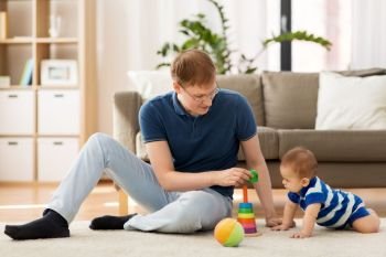 family, fatherhood and people concept - happy father with little baby son playing with toys at home. happy father with little baby son playing at home