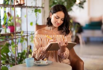 people, leisure and inspiration concept - happy woman with notebook at coffee shop or cafe. happy woman with notebook at coffee shop or cafe