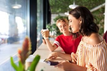 people, cash payment and finances concept - female friends paying by credit card for coffee at cafe. female friends paying by credit card at cafe