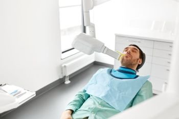 medicine, dentistry and healthcare concept - male patient having x-ray scanning procedure at dental clinic. patient having x-ray scanning at dental clinic