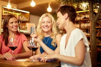 leisure, cashless payment and lifestyle concept - happy women with credit card paying bill at restaurant or wine bar. women with credit card at wine bar or restaurant