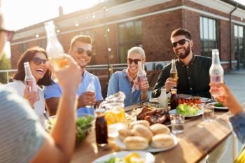 leisure and people concept - happy friends with drinks having barbecue party on rooftop. happy friends with drinks or bbq party on rooftop