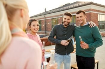 leisure and people concept - happy friends with drinks hugging at rooftop party. happy friends with drinks hugging at rooftop party