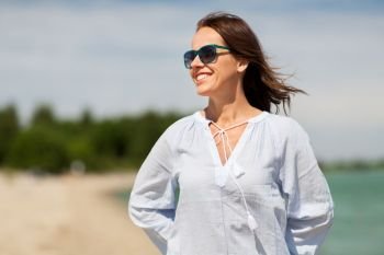 people and leisure concept - happy smiling woman in sunglasses on summer beach. happy smiling woman in sunglasses on summer beach