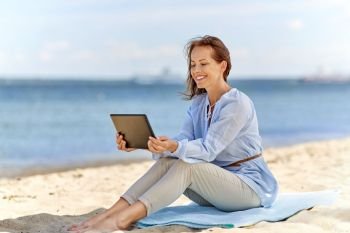 technology, people and leisure concept - happy smiling woman with tablet pc computer on summer beach. happy smiling woman with tablet pc on summer beach