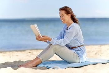 people and leisure concept - happy smiling woman reading book on summer beach. happy smiling woman reading book on summer beach