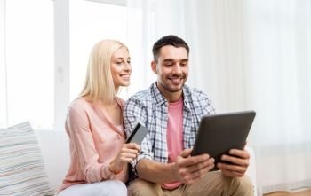 technology, online shopping and people concept - smiling happy couple couple with tablet pc computer and credit card at home. couple with tablet pc and credit card at home