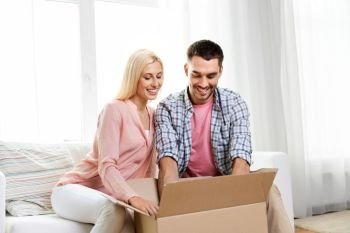 delivery, mail and people concept - happy couple with open parcel box at home. happy couple with open parcel box at home