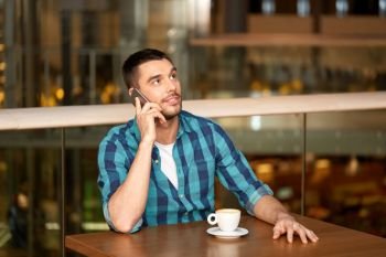 people, communication and leisure concept - happy man drinking coffee at restaurant and calling on smartphone. man with coffee calling smartphone at restaurant