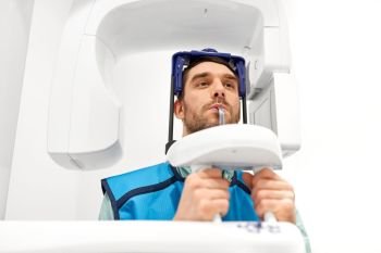 medicine, dentistry and healthcare concept - male patient having panoramic x-ray scanning procedure at dental clinic. patient having x-ray scanning at dental clinic
