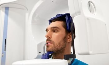 medicine, dentistry and healthcare concept - male patient having panoramic x-ray scanning procedure at dental clinic. patient having x-ray scanning at dental clinic