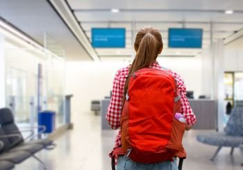 travel, tourism and people concept - young woman with red backpack over airport terminal background. young woman with backpack over airport terminal