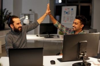 deadline, teamwork and success concept - creative team with computers making high five at night office. creative team making high five at night office
