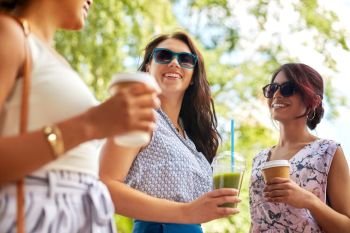 leisure, people and friendship concept - happy women or friends with takeaway drinks talking summer park. happy women or friends with drinks at summer park