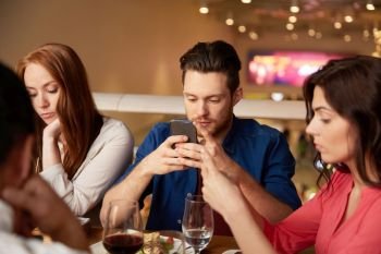 leisure, technology, lifestyle and people concept - friends with smartphones dining at restaurant. friends with smartphones at restaurant