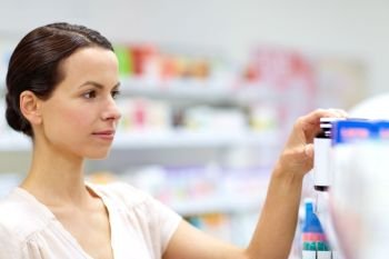 medicine, pharmaceutics, healthcare and people concept - female customer choosing drugs at pharmacy. female customer choosing drugs at pharmacy