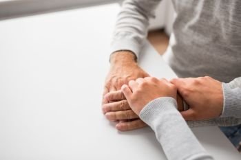 old age, family, care and support concept - close up of young woman holding senior man hands. close up of young woman holding senior man hands