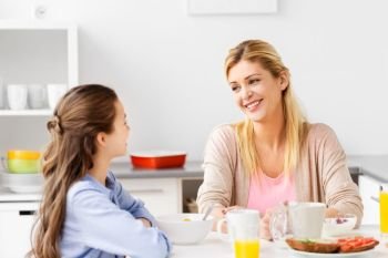 food, healthy eating, family and people concept - happy mother and daughter having breakfast at home kitchen. happy mother and daughter having breakfast at home