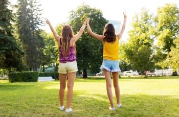 leisure, people and friendship concept - happy teenage girls or friends showing peace hand sign at summer park. teenage girls showing peace hand sign at park