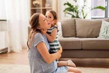 pregnancy, people and family concept - happy pregnant mother and little daughter hugging at home. pregnant mother and daughter hugging at home