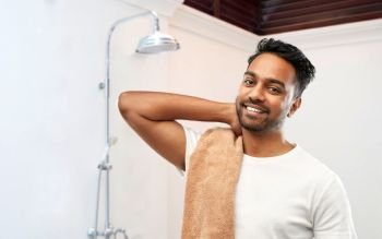 grooming, hygiene and people concept - smiling indian man with bath towel over shower background. smiling indian man with bath towel over shower