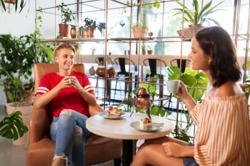 people, communication and friendship concept - female friends drinking tea and talking at cafe. female friends drinking tea and talking at cafe