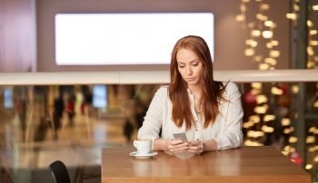 people, technology and leisure concept - woman drinking coffee and messaging on smartphone at restaurant or cafe. woman with coffee and smartphone at restaurant