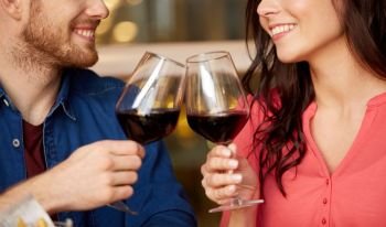 celebration, holidays and people concept - happy couple drinking red wine at restaurant. happy couple drinking red wine at restaurant