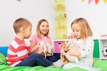 childhood, leisure and people concept - happy children playing with soft toys at home. happy children playing with soft toys at home