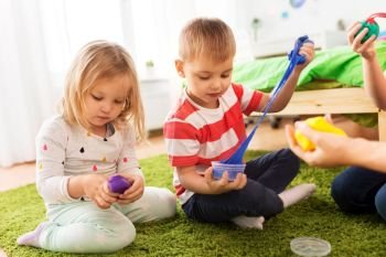 childhood, leisure and people concept - children playing with modelling clay or slimes at home. children with modelling clay or slimes at home