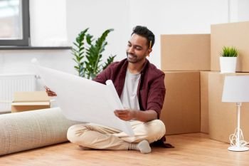 moving, people and real estate concept - happy indian man with boxes and blueprint at new home. man with boxes and blueprint moving to new home