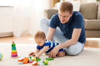 family, fatherhood and people concept - happy father with little baby son playing with toy blocks at home. happy father with baby son playing toys at home