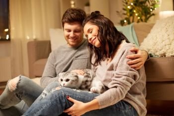 pets, hygge and people concept - happy couple with cat at home. happy couple with cat at home