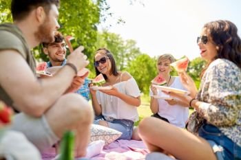 friendship, leisure and food concept - group of happy friends eating watermelon at picnic in summer park. happy friends eating watermelon at summer picnic