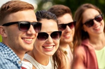 leisure, people and friendship concept - happy teenage friends in sunglasses outdoors in summer. happy teenage friends in sunglasses outdoors