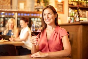 people, alcohol and lifestyle concept - happy woman drinking red wine at restaurant or bar. happy woman drinking red wine at bar or restaurant
