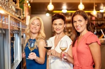 people, alcohol and lifestyle concept - happy women drinking wine at bar or restaurant. happy women drinking wine at bar or restaurant