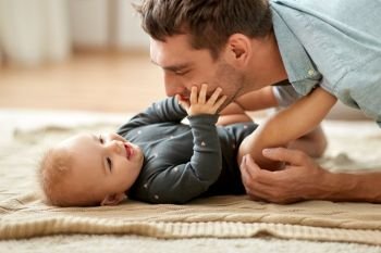 family, fatherhood and people concept - father playing with little baby daughter at home. father playing with little baby daughter at home