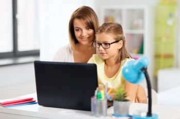 education, family and learning concept - mother and daughter with laptop computer doing homework together at home. mother and daughter with laptop doing homework