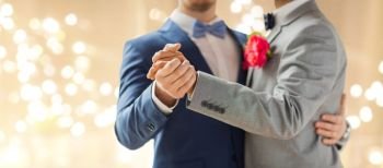 lgbt, homosexuality and same-sex marriage concept - close up of happy male gay couple holding hands and dancing on wedding over festive lights background. close up of happy male gay couple dancing
