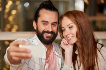 leisure, technology and people concept - happy couple taking selfie by smartphone at restaurant. couple taking selfie by smartphone at restaurant