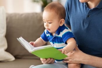 family, parenthood and people concept - happy asian baby boy and father with book at home. baby boy and father with book at home
