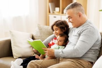 family, fatherhood and people concept - happy father with preteen and baby son reading book at home. happy father with sons reading book at home